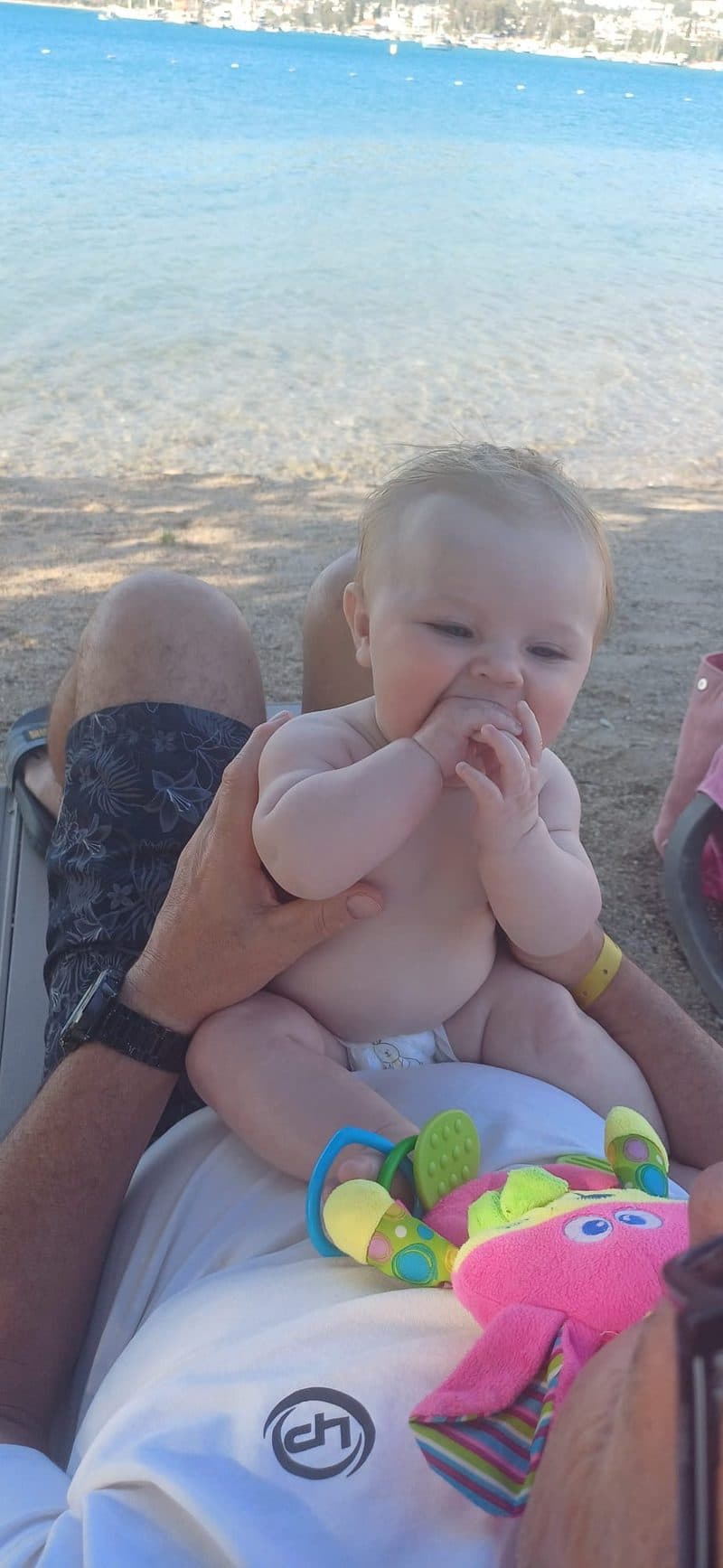 4-month-old baby on grandad's lap on a sunlounger at the beach in Akbuk Turkey