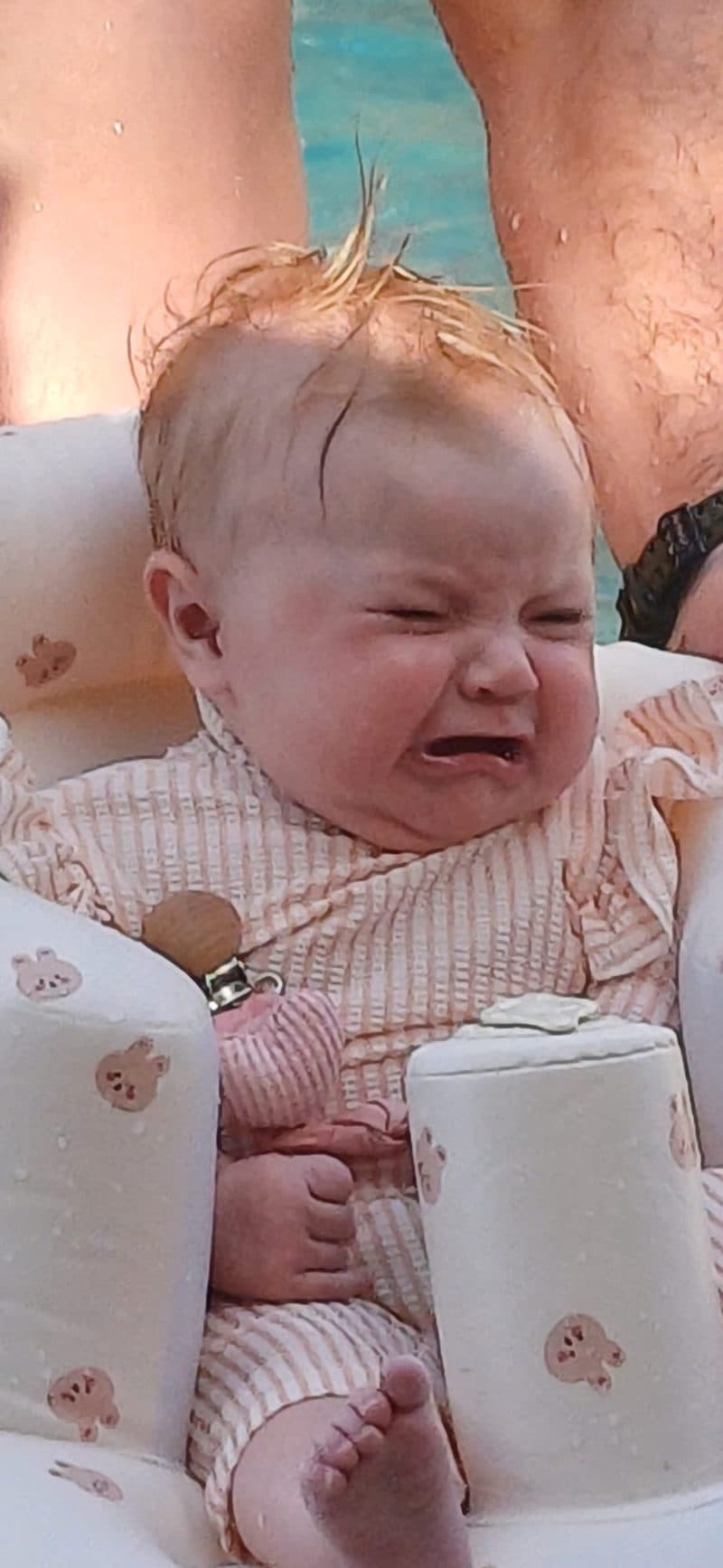 Baby crying in inflatable float in the resort pool in Turkey - water too cold in May for a 4-month-old