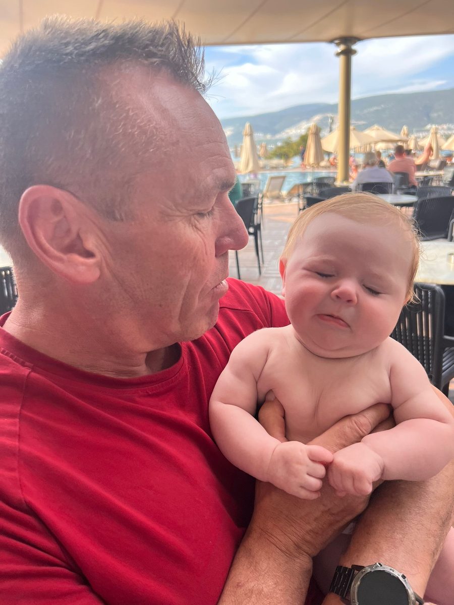 Grandad holding 4-month-old baby at Long Beach Club Nature resort restaurant in Akbuk Turkey