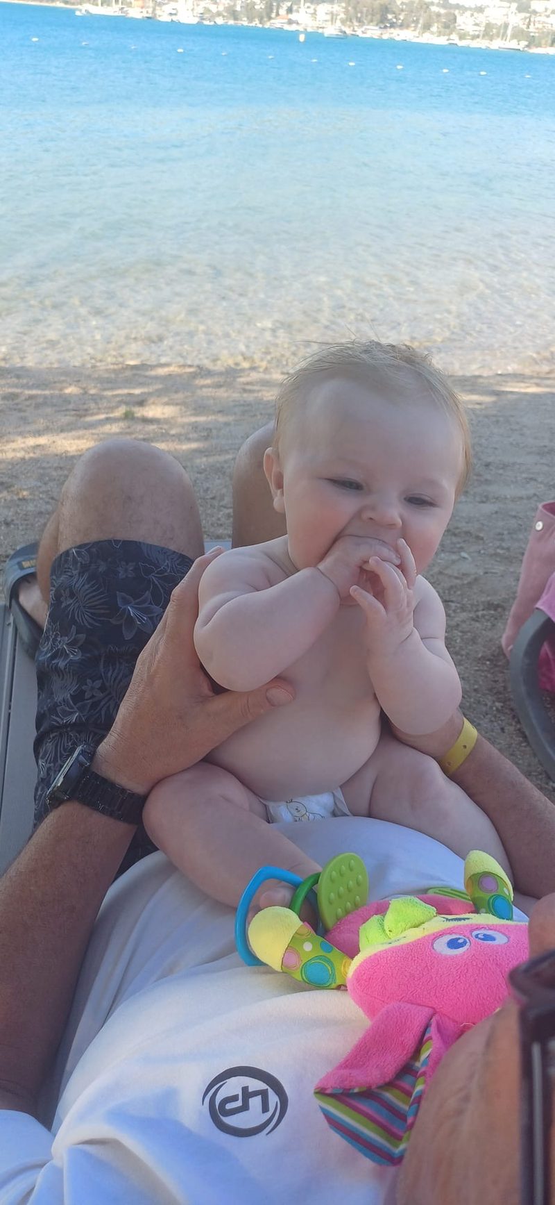 4-month-old baby on grandad's lap on a sunlounger at the beach in Akbuk Turkey